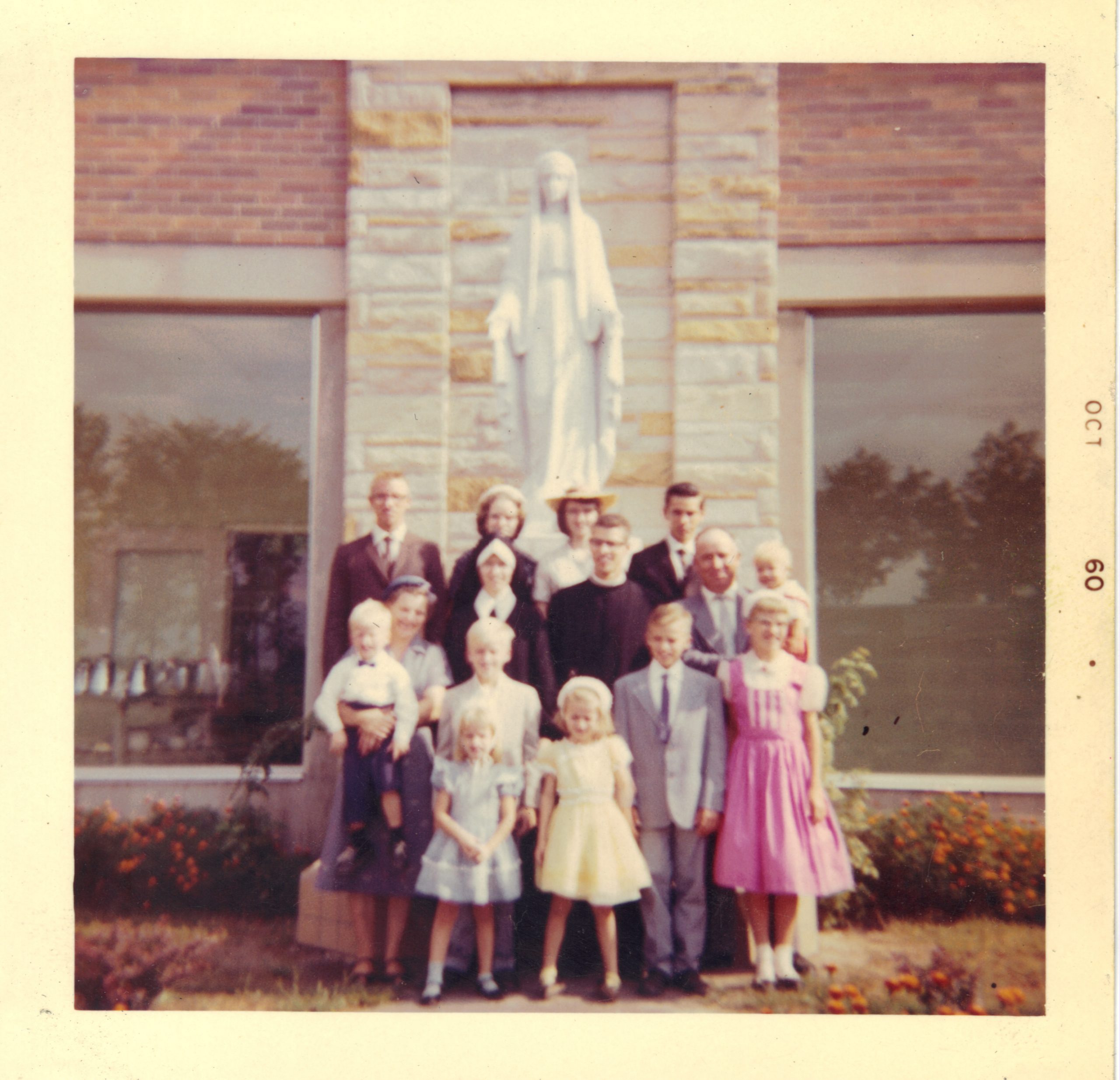 Fr David and his family stand in front of a statue of Mother Mary. This color photo from 1960 is a bit blurry.