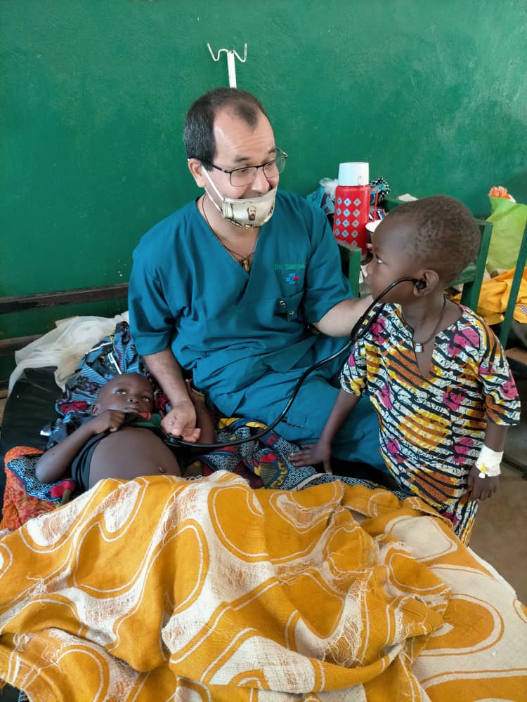 Comboni Brother Dr. Salgado lets a little boy listen to his brothers heartbeat with a stethascope.