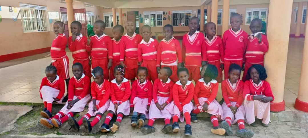 Students at St. Monica's Kindergarten in Gulu pose for a class photo in their red and pink uniforms.
